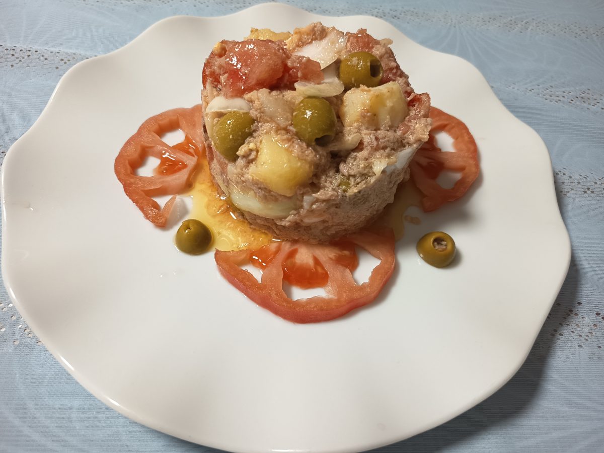 Receta de picadillo de atún acabado puesto en un plato llano de color blanco.
