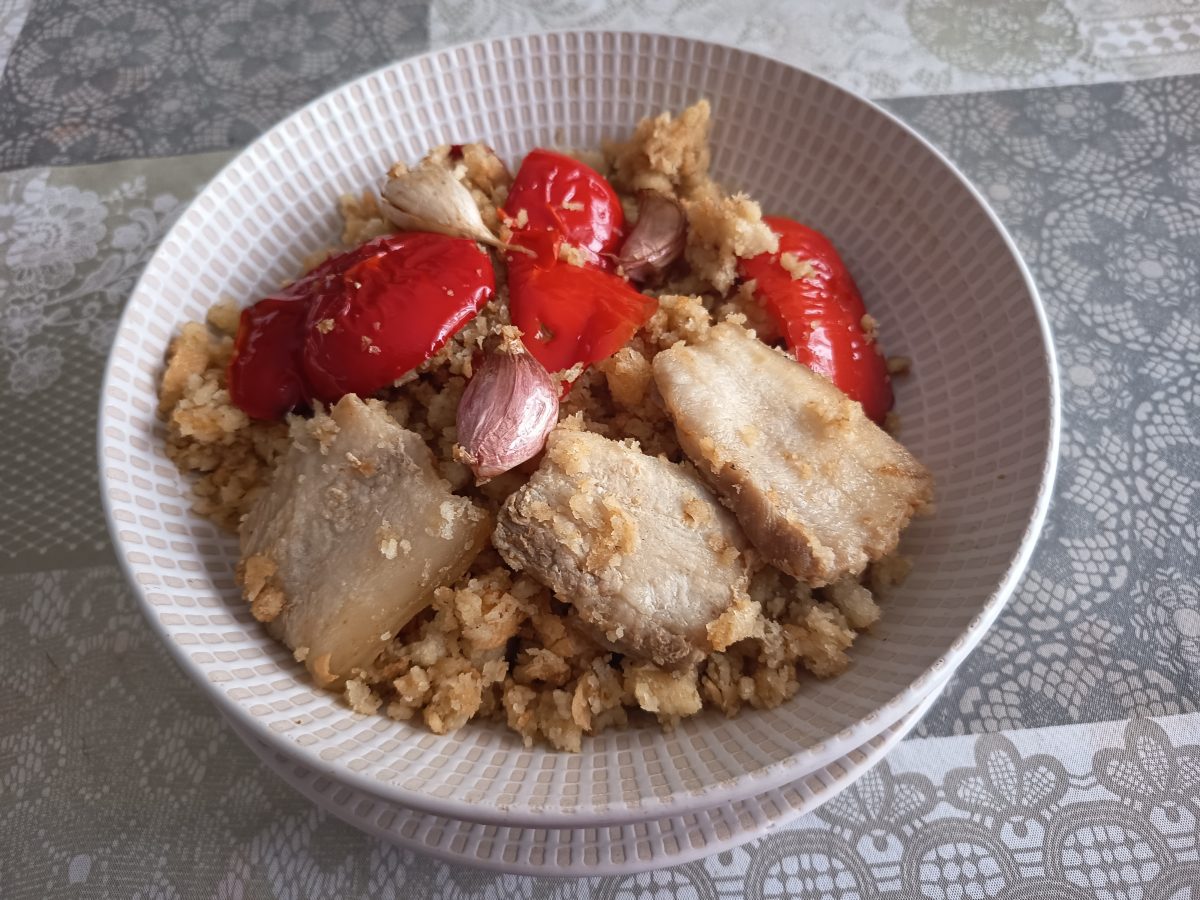 Migas extremeñas acabadas puestas en un plato hondo con su guarnición.