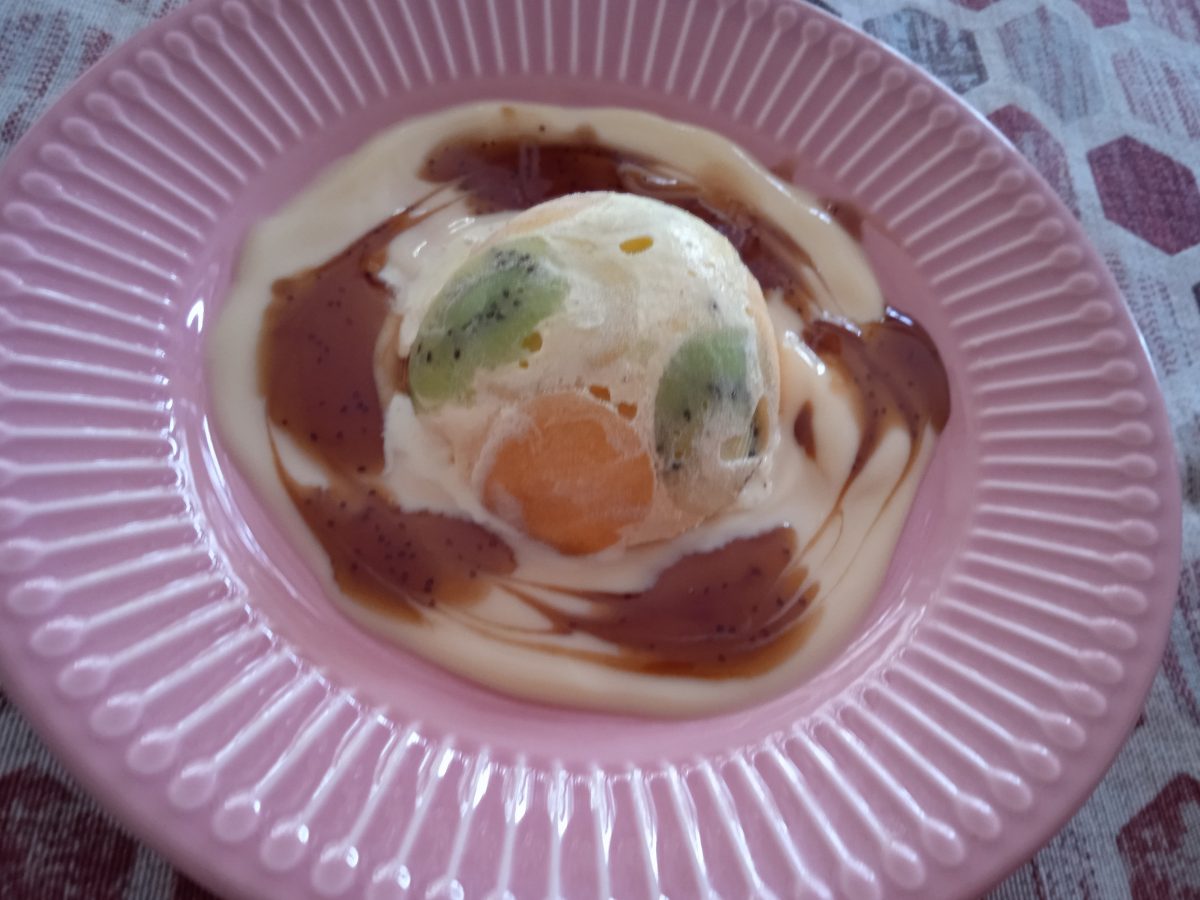 Receta de semiesfera de helado artesanos acabada puesta en un plato de color rosa.