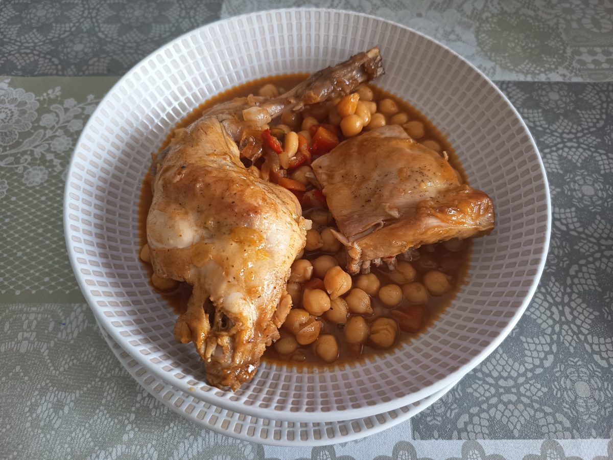 Receta de estofado de garbanzos con conejo acabada y puesto en un plato hondo listo para comerlo.