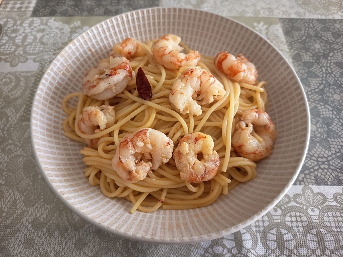 Receta de espaguetis con gambas al ajillo al que le hemos añadido crema de gambas acabada y puesta en un plato hondo.