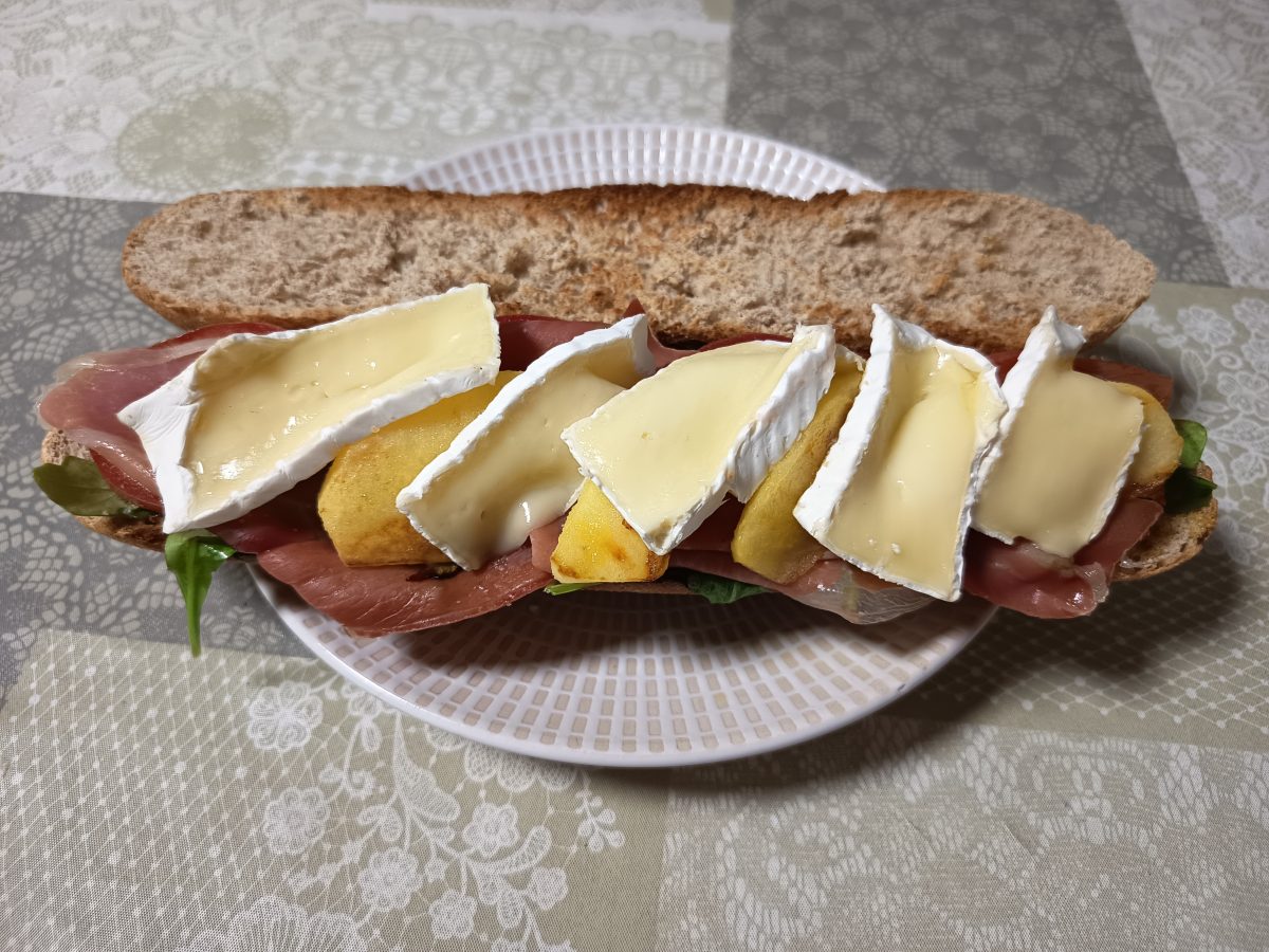 receta de bocadillo de jamón serrano y queso brie acabado puesto en un plato llano listo para comerlo