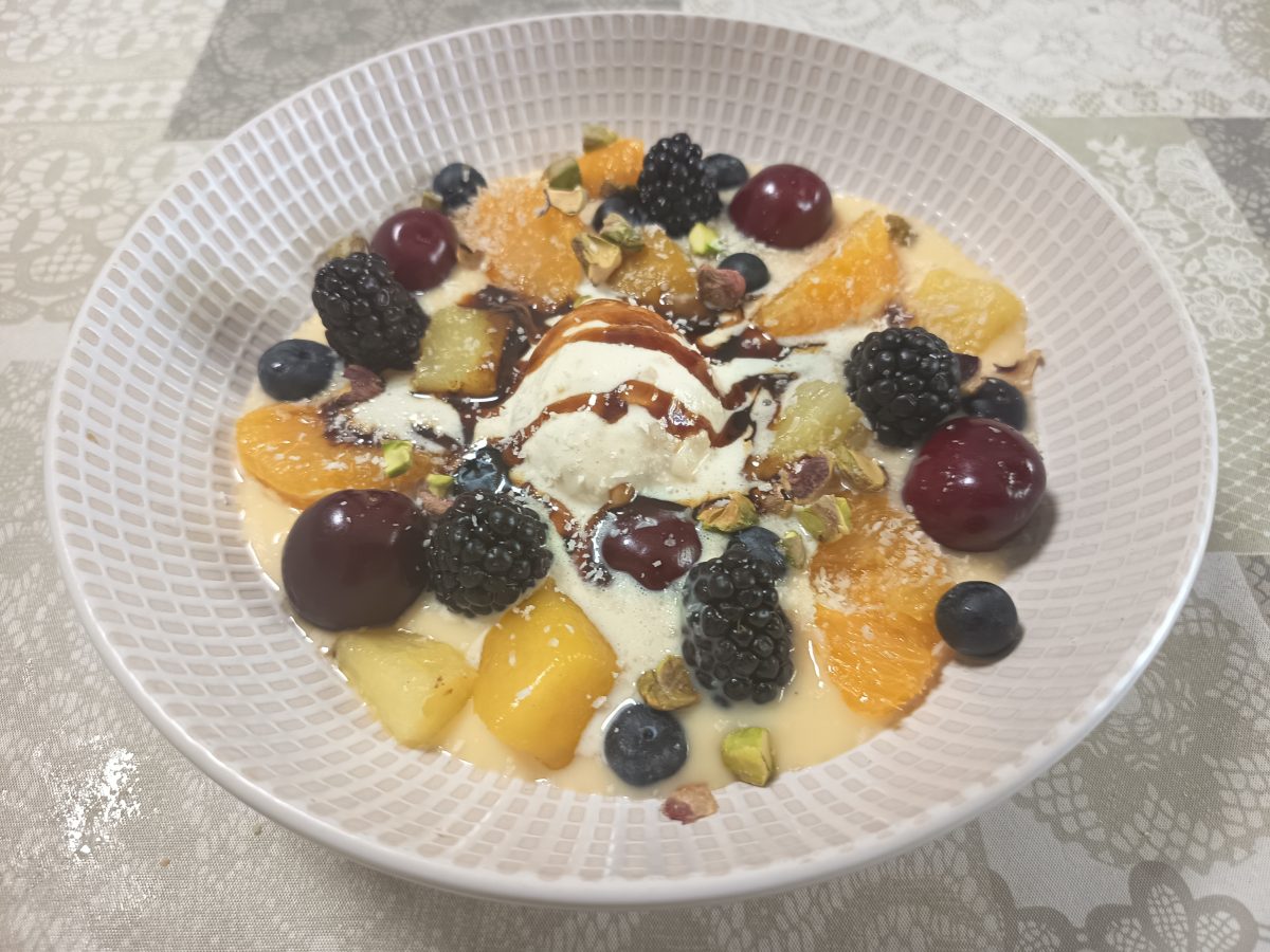 Receta de crema ligera con frutas y helado de vainilla puesto en un plato hondo listo para servirla.