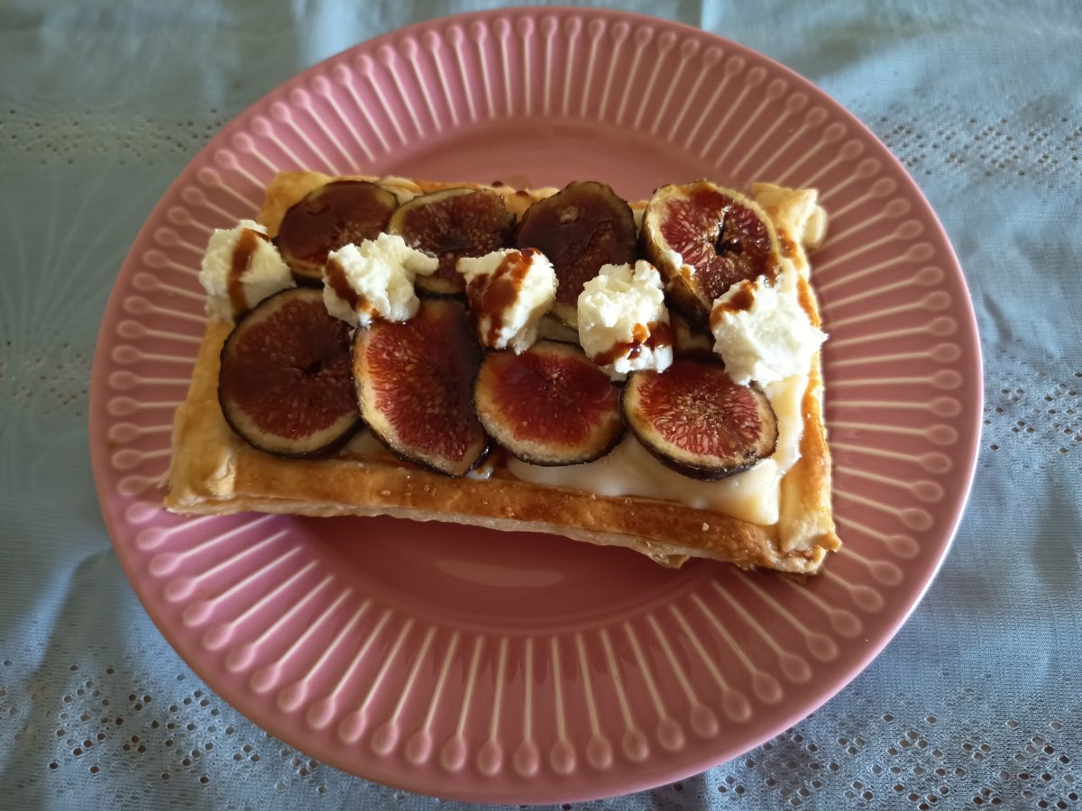 banda de hojaldre con crema y higos acabada puesta en un plato de postre lista para servir.