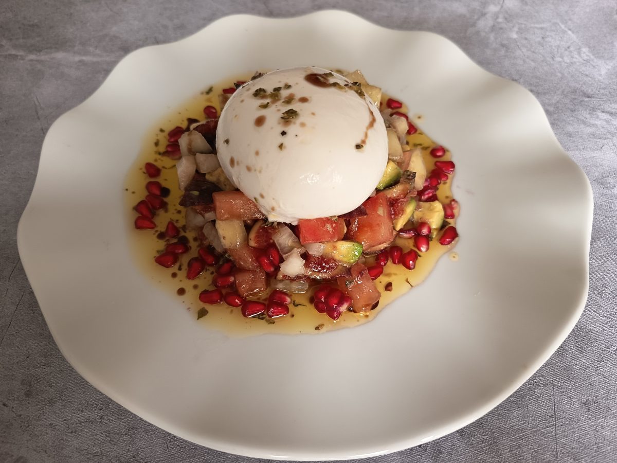 receta de tartar de higos y burrata acabada y puesto en un plato llano de color blanco.